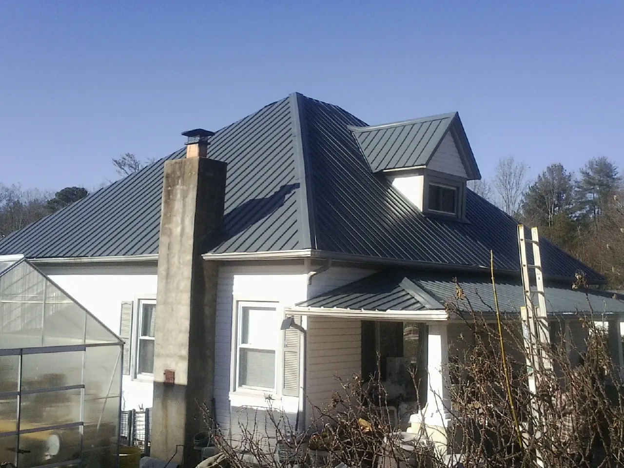 Dark blue standing seam metal roof on a white farmhouse with dormer — Slate & Tile Roof Repair by Roofing Brothers in Bishop