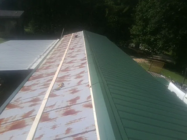 Old rusted panels beside newly installed green metal roofing — Wind Damage Roof Repair by Roofing Brothers in Bishop