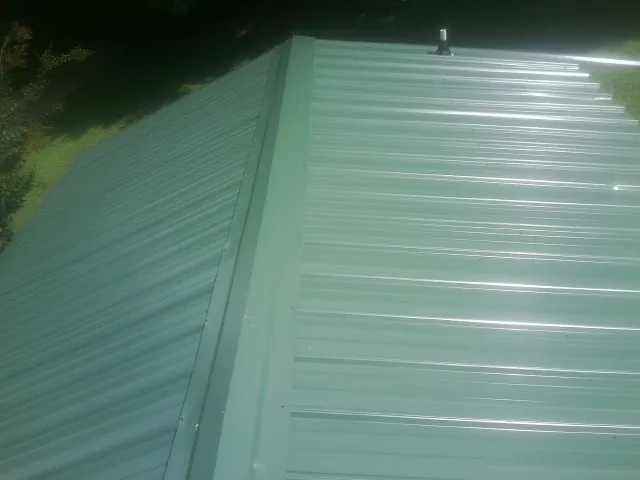 New green metal panels meeting at the ridge of a roof — Flat Roof Repair work by our crew in Bishop