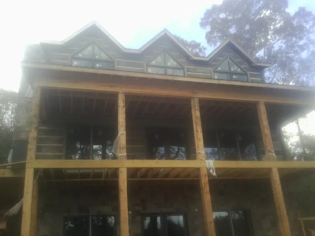Dormers and porch framing on a large log home under construction — Roof Coating work by our crew in Bishop