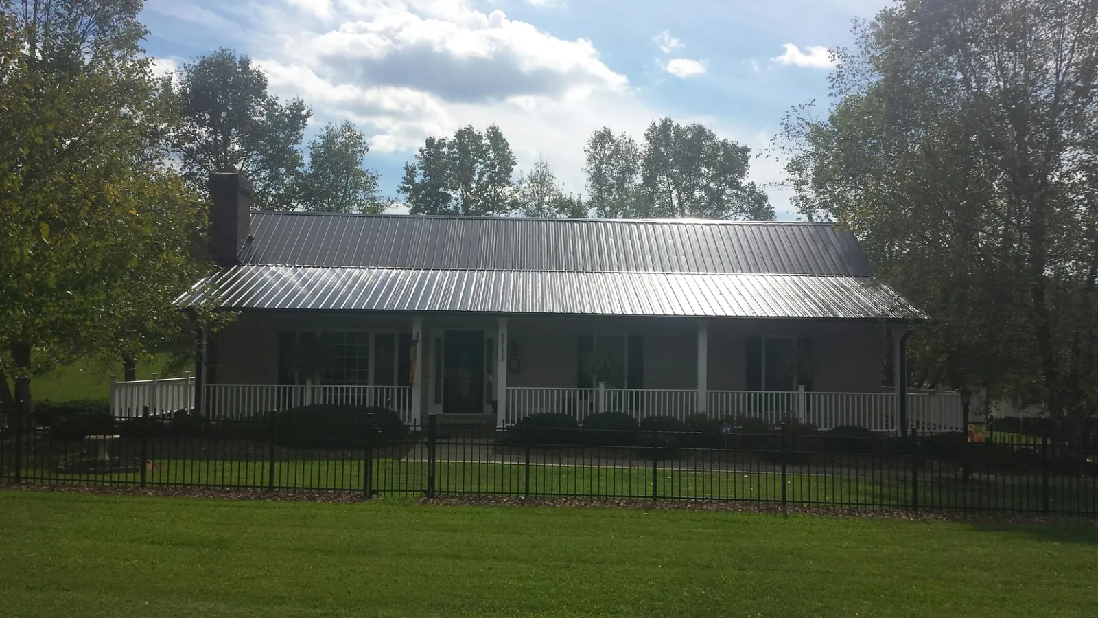 Gray metal roof on a brick ranch with a full width front porch — Gutter Guard Installation work by our crew in Bishop